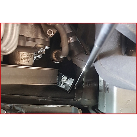 Nahaufnahme eines Motorraums mit verschiedenen Komponenten. Ein Werkzeug wird in das Bild gehalten.